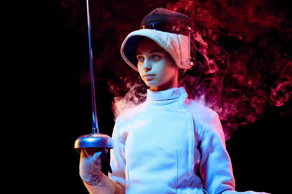 teen girl fencing costume with sword hand isolated black wall